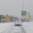 Un vehículo se aproxima a una curva sobre la calzada nevada en Dedham, Massachussets.