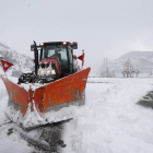 Un tractor retira nieve con una cuña en una carretera junto al pantano de Los Barrios de Luna. JESÚS