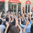 Los activistas alzan las manos simulando ser víctimas de un atraco de la banca.