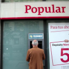 Un hombre saca dinero de un cajero del Popular en Madrid.