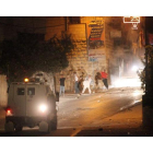 Jóvenes palestinos lanzan piedras contra soldados israelís en la ciudad de Hebron.