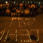 Un grupo de personas rezan ante las velas con la frase "Rezar por MH370" durante una vigilia en memoria de los 239 pasajeros y tripulación que viajaban a bordo del avión de Malaysia Airlines desaparecido el sábado