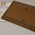 Imagen de las instrucciones y el tablero con las fichas del ‘Ludus Latrunculorum’. Los jugadores deberán elegir uno de los dos bandos (la Legio VI Victrix o la Legio VII Gémina, cada una identificada con su propio emblema) para capturar la ma