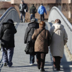 Varias personas mayores cruzan uno de los puentes peatonales sobre el Bernesga.