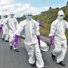 Personal protegido con trajes especiales retira el cuerpo de un fallecido por ébola en Monrovia (Liberia).