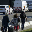 Varias personas caminan hacia la terminal mientras los vehículos hacen cola en un control de seguridad, en el aeropuerto de Zaventem, este lunes.