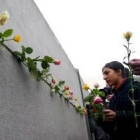 Jóvenes alemanes colocan flores en un trozo del muro