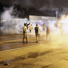 Manifestantes protestan por las calles de Ferguson entre columnas de humo, este sábado por la noche.