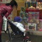 Una mujer acerca a su hija a un escaparate para que vea los juguetes que le traerán los Reyes Magos