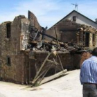 Dos vecinos de Castropodame contemplan el estado de ruina de las tres viviendas calcinadas