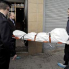 Miembros de la funeraria trasladan el cuerpo de uno de los dos miembros del matrimonio asesinado aye