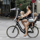 Una mujer y dos niñas circulan en bicicleta por el carril ciclista del paseo de Sant Joan de Barcelona.