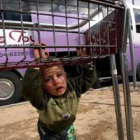 Un palestino juega mientras su familia carga sus pertenencias en un bus que los sacará de Gaza.