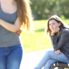 Una chica sentada en el parque siente envidia al ver a una pareja.