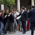 Carles Puigdemont, junto al vicepresidente Oriol Junqueras (c), y el conseller de Presidencia, Jordi Turull (i), saluda a los trabajadores de la Generalitat que les han recibido con aplausos a su llegada a la reunión extraordinaria del Govern.
