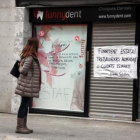 Una joven mira las pancartas de protesta en la fachada de la clínica dental que Funnydent tenía en Mataró.