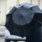 Un hombre se protege del viento y la lluvia en Ponferrada