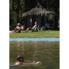 Dos mujeres toman el sol mientras un niño se da un chapuzón en la playa fluvial de Quintanilla de Sollamas.