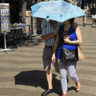 Una pareja se protege del sol con un paraguas.