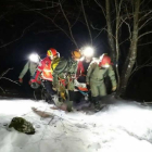 Componentes del Greim de Sabero ayudados por compañeros de la montañera accidentada, portean a la herida a través de la nieve.