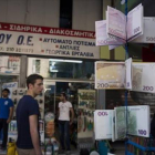 Ciudadanos griegos pasean ante carteras con el diseño del euro en un quiosco del centro de Atenas, este martes.