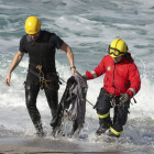 Miembros del cuerpo de Bomberos retiran restos de ropa de la playa del Orzán.