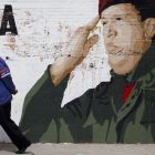 Un hombre pasea frente a un mural de Chavez.