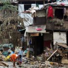 Los filipinos limpian de agua y barro una zona inundada cerca de sus viviendas.