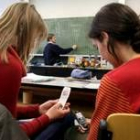 Dos estudiantes usan sus móviles durante una clase en el instituto