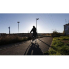 Un hombre circula en bicicleta por una carretera de León