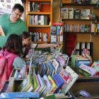 Unos jóvenes lectores curiosean libros en una caseta. RAMIRO