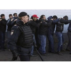 Un agente de policía vigila a varios de los inmigrantes detenidos en la redada masiva, este lunes en Moscú.