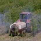 La imagen muestra a un agricultor tratando una plantación de frutales