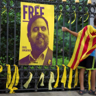 Un niño pone un lazo amarillo junto a un cartel de ‘Liberad a Junqueras’. ENRIC FONTCUBERTA