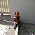 La pequeña Shivani, de 15 meses, atada con una cinta a una piedra mientras su madre trabaja.