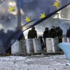 Varios policías antidisturbios montan un cordon policial tras una bandera de la Unión Europea cerca de una de las barricada un nuevo día de protestas contra el gobierno en el centro de Kiev