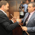 López Riesco tiende la mano a Ismael Álvarez mientras éste le hace entrega el bastón de mando, ambos