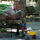 Un abuelo lee el periódico en un parque de Madrid.