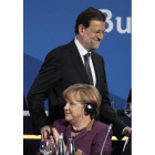Rajoy, hace un gesto de saludo a Merkel, ayer, en Bucarest.