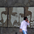 Un hombre pasa frente a un muro con los retratos de tres de los seis jesuitas asesinados en El Salvador en 1989, este miércoles.