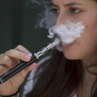 Una mujer exhala vapor de un cigarrillo electrónico.