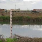 Una de las balsas de decantación y, al fondo, una instalación ganadera en las afueras de la ciudad