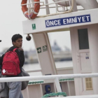 Un migrante pakistaní mira hacia atrás, conducido por un funcionario, en el ferri a punto de partir hacia Turquía, en Lesbos, este viernes.