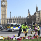 El terrorista Khalid Masood y unos policías colocan flores en un altar improvisado. EFE / HANNAH MCKAY