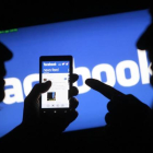 Dos usuarios consultan a través de sus teléfonos móviles la aplicación de Facebook.