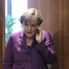 Angela Merkel despacha con su móvil.