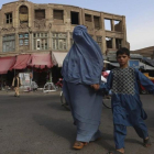 Una mujer afgana vestida con un burka agarra de la mano a su hijo al cruzar una calle en Herat, Afganistán, este jueves.