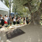 Familiares depositan flores ante la placa.