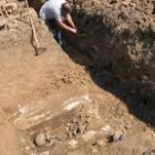 Un arqueólogo señala varias tumbas en la pared de la zanja hecha para la canalización del gas