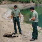 Dos agentes medioambientales investigan a un ave rapaz muerta